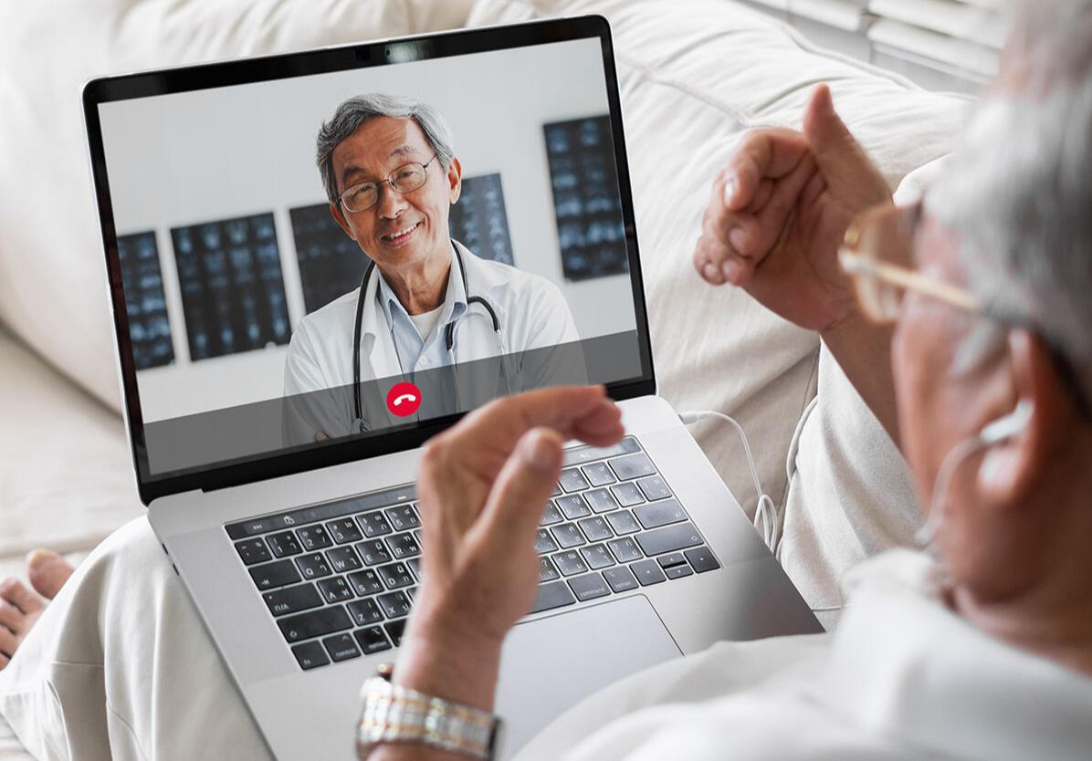 An older adult receiving friendly help while using a laptop